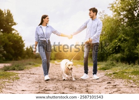 Dog-Friendly Date Concept. Two young people walking dog on a leash, looking at each other, holding hands
