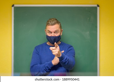 Dogmatic Male Teacher Pointing At The Camera With An Intense Expression While Wearing A Face Mask During The Covid-19 Pandemic