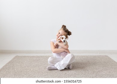 Dogs, Children And Pets Concept - Little Child Girl Sitting On The Floor With Cute Puppy