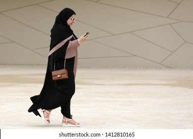 Doha, Qatar - 11 April, 2019: A Qatari woman in a long black dress called abayha walks around The National Museum of Qatar.