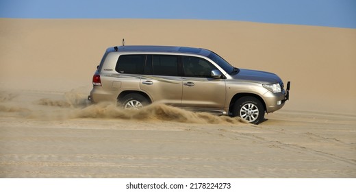 Doha, Qatar, Circa 2021: A 4x4 Sports Utility Vehicle (SUV) Speeding Over Sand Dunes. Sand Spraying From The Car's Wheels. Sand Dune Driving (bashing) Is A Popular Weekend Activity In Qatar. 