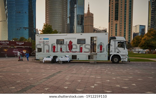 Doha, Qatar-\
February 2 2021: Blood donation campaign in Doha Qatar with blood\
donation mobile unit from Hamad medical corporation standing in\
Sheraton park with skylines in\
background