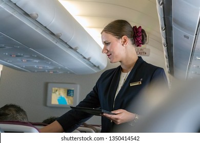 Doha, Qatar - February 20th, 2019: A Female Cabin Crew Flight Attendant Speaking With A Passenger Onboard On Airbus A350 Of Qatar Airways.