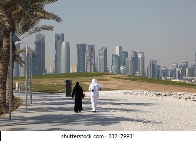 DOHA, QATAR - JAN 8: Arabic couple walking in front of the Doha downtown skyline. January 8, 2012 in Doha, Qatar, Middle East