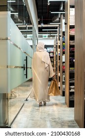 Doha, Qatar - January 01, 2021: Young Lady in Abaya in shopping Mall with Paper shopping bag