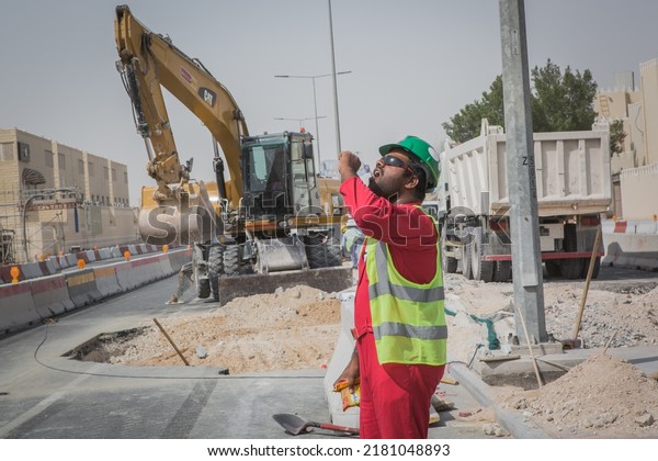 DOHA, QATAR - JULY 27, 2019: Construction workers\
on duty in Qatar, the first Middle Eastern country to host the FIFA\
World Cup in 2022. Qatar is accused of failing to stop migrant\
workers\' abuses.