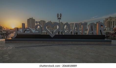 Doha, Qatar- October 31 2021: Porto Arabia  in The pearl Doha, Qatar sunset shot showing  Love QATAR sign in Arabic and English in foreground with Yachts ,boats and residential buildings in background
