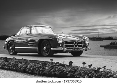 Doha, year 2019: front view of a Mercedes-Benz 300SL Gullwing. Grayscale picture of a classic supercar, expensive model. Sea and ships on the background