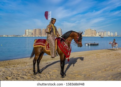 Doha,Qatar-December 18,2013: A Qatari Man Riding A Horse And Carry Qatar Flag In Katara Beach Celebrating Qatar National Day