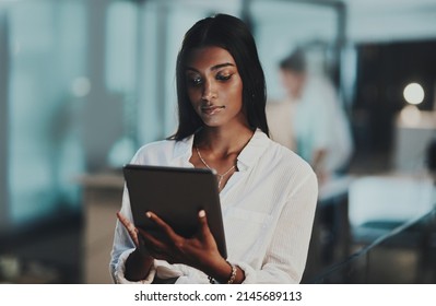 Doing It All At Once With Modern Tech. Shot Of A Young Businesswoman Using A Digital Tablet In An Office At Night.