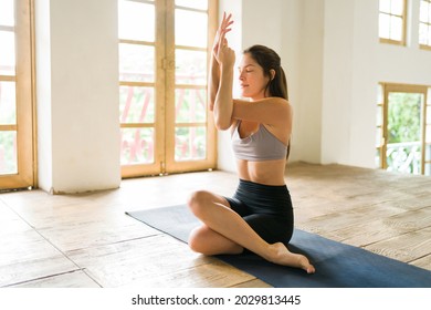 Doing breathing exercises. Serene young woman practicing an eagle pose while sitting on a yoga mat - Powered by Shutterstock