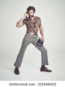 Doing everything with flair. A handsome man on a retro telephone while striking a pose.