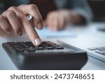 Doing finance, budgeting and tax calculation. Close up woman hand using calculator to calculate home finance, accounting with laptop computer on table, budget management, monthly expenses