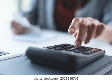 Doing finance, budgeting and tax calculation. Close up woman hand using calculator to calculate home finance, accounting with laptop computer on table, budget management, monthly expenses