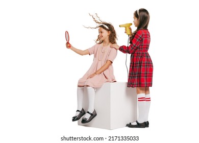 Doing Hair. Studio Shot Of Little Happy Girls In Retro Style Outfit, Fashion Of 70s, 80s Years Isolated On White Background. Concept Of Emotions, Facial Expression, Beauty. Copy Space For Ad