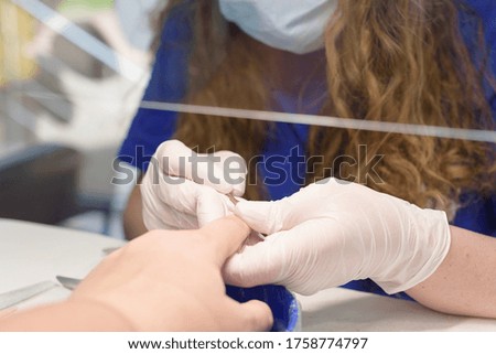 doing a manicure in a beauty salon with a mask and a protective screen in the new reality after the coronavirus pandemic