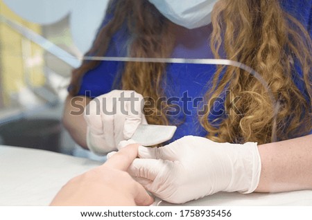 doing a manicure in a beauty salon with a mask and a protective screen in the new reality after the coronavirus pandemic