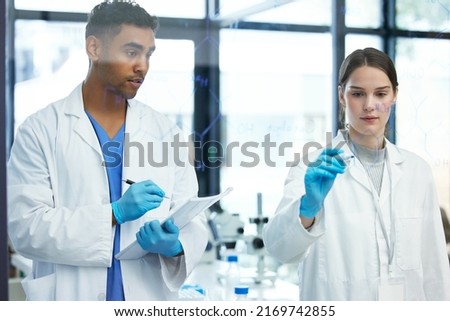 Doing the maths to prove their theory. Shot of two scientists solving equations on a glass screen in a laboratory.