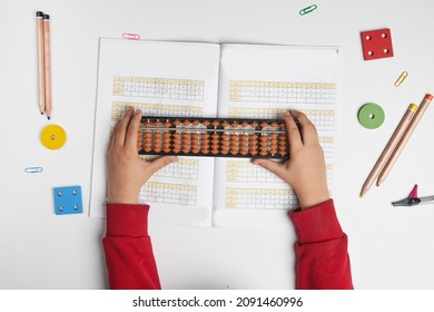 Doing mental math or mental arithmetic. Hand of little boy using abacus for calculating. Learning to use abacus on mental math courses. A kid doing math at home with abacus