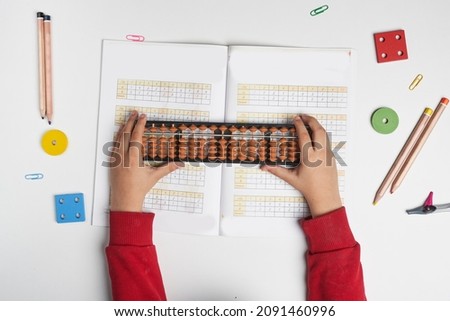 Doing mental math or mental arithmetic. Hand of little boy using abacus for calculating. Learning to use abacus on mental math courses. A kid doing math at home with abacus