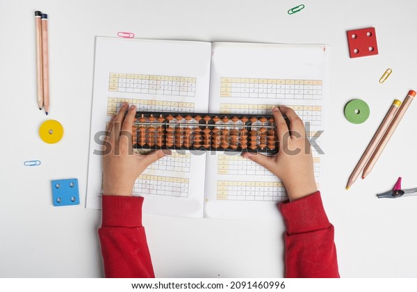 Doing mental math or\
mental arithmetic. Hand of little boy using abacus for calculating.\
Learning to use abacus on mental math courses. A kid doing math at\
home with abacus
