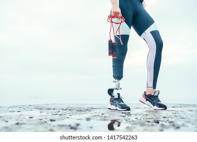 Doing my best. Cropped image of disabled woman in sports clothing with prosthetic leg holding skipping rope while standing in front of the sea. - Powered by Shutterstock