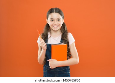 Doing Research. Literature Lesson. Back To School. Happy Little Girl With Notebook. School Girl Read Book On Orange Background. Writing Notes. Kid Diary. Poetry And Novel. Modern Education.