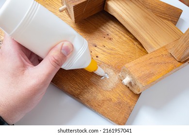 Do-it-yourself home furniture repair, giving old things new life concept image. Person's hands applying white glue on broken wooden furniture.