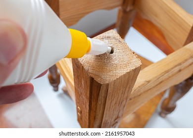 Do-it-yourself home furniture repair, giving old things new life concept image. Person's hands applying white glue on broken wooden furniture.