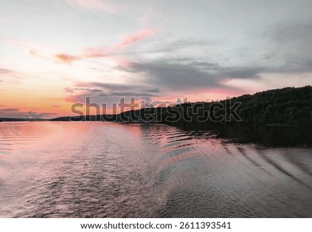 Doldrums and ripples from the waves on the surface of the water from a ship sailing away on a pink sunset, river trip.