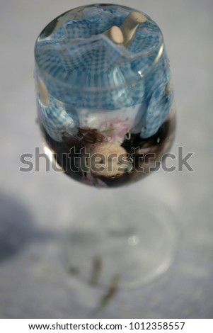 doll in blue dress drowning up side down in a glass on a sunny day