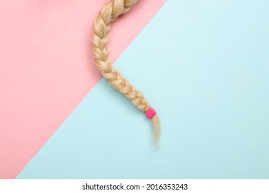 doll hair braid on a blue pink pastel background. Hair care, minimalistic beauty concept