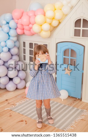 Doll house in girl play room decorated with rainbow balloons. Baby girl in the room