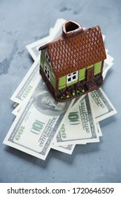 Doll House On A Stack Of American 100 Dollar Bills, Studio Shot On A Grey Concrete Background, Selective Focus