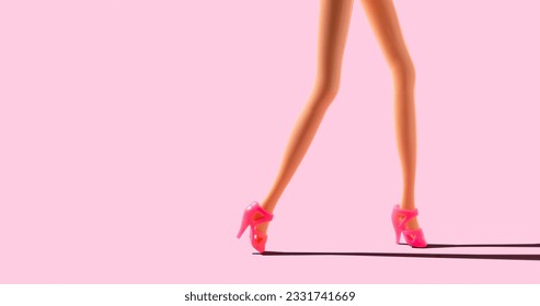 Doll legs on pink background, copy space.