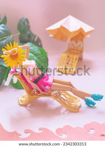 Doll on a sun lounger, pink color, beach umbrella and sunglasses - beach vacation
