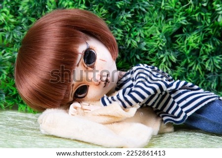 doll red hairs girl lying toy in green plastic background