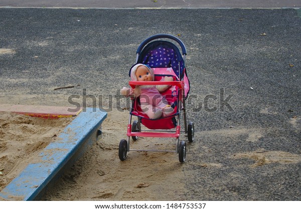 doll in a stroller near\
the sandbox