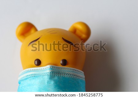 A doll wearing COVID19 mask and maintaining safety , background with light color