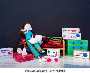 Doll woman sitting on a couch covering her face with a tissue, surrounded by boxes with cold medicines and flu medicines. Used tissues and tissues boxes on the floor. Room for text. Black wall.