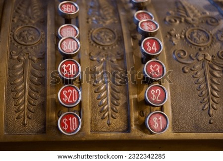 Dollar amounts on red round keys of an antique gold cash register