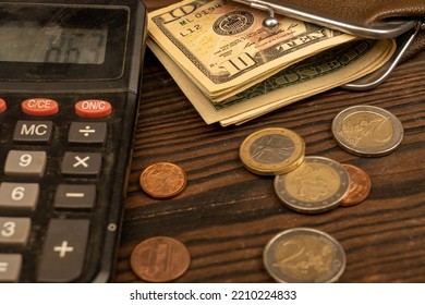 Dollar banknotes, euro coins, a vintage brown leather wallet and a calculator on a wooden surface. Close-up, selective focus. - Powered by Shutterstock