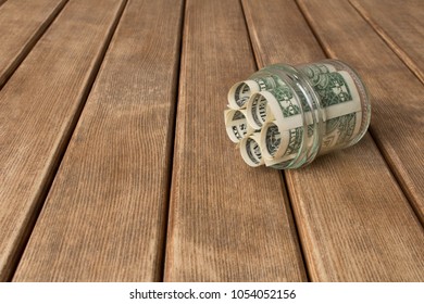 Dollar bills in a glass jar on a wooden table . The concept of poverty .