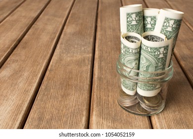 Dollar bills in a glass jar on a wooden table . The concept of poverty .