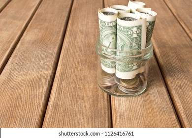 Dollar bills in a glass jar on a wooden table . The concept of poverty .