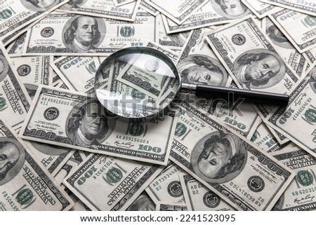 Dollar bills and a magnifying glass on the table