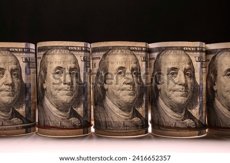 Dollar bills rolled into rolls standing in a row in backlight. Finance and economics concept. Selective focus.