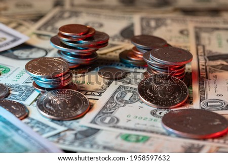 Dollar coins on US dollar banknotes. Piled up coins symbol for prosperity. Half dollar coins in front on top of spread out dollar banknotes