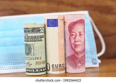 Dollar, Euro, And Yuan Currency In Front Of Face Mask Reflects Global Investment In Public Health Protection And Vaccine Immunzation Across Borders