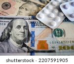 Dollars as a background for white pill packs as a symbol of rising medical and healthcare costs